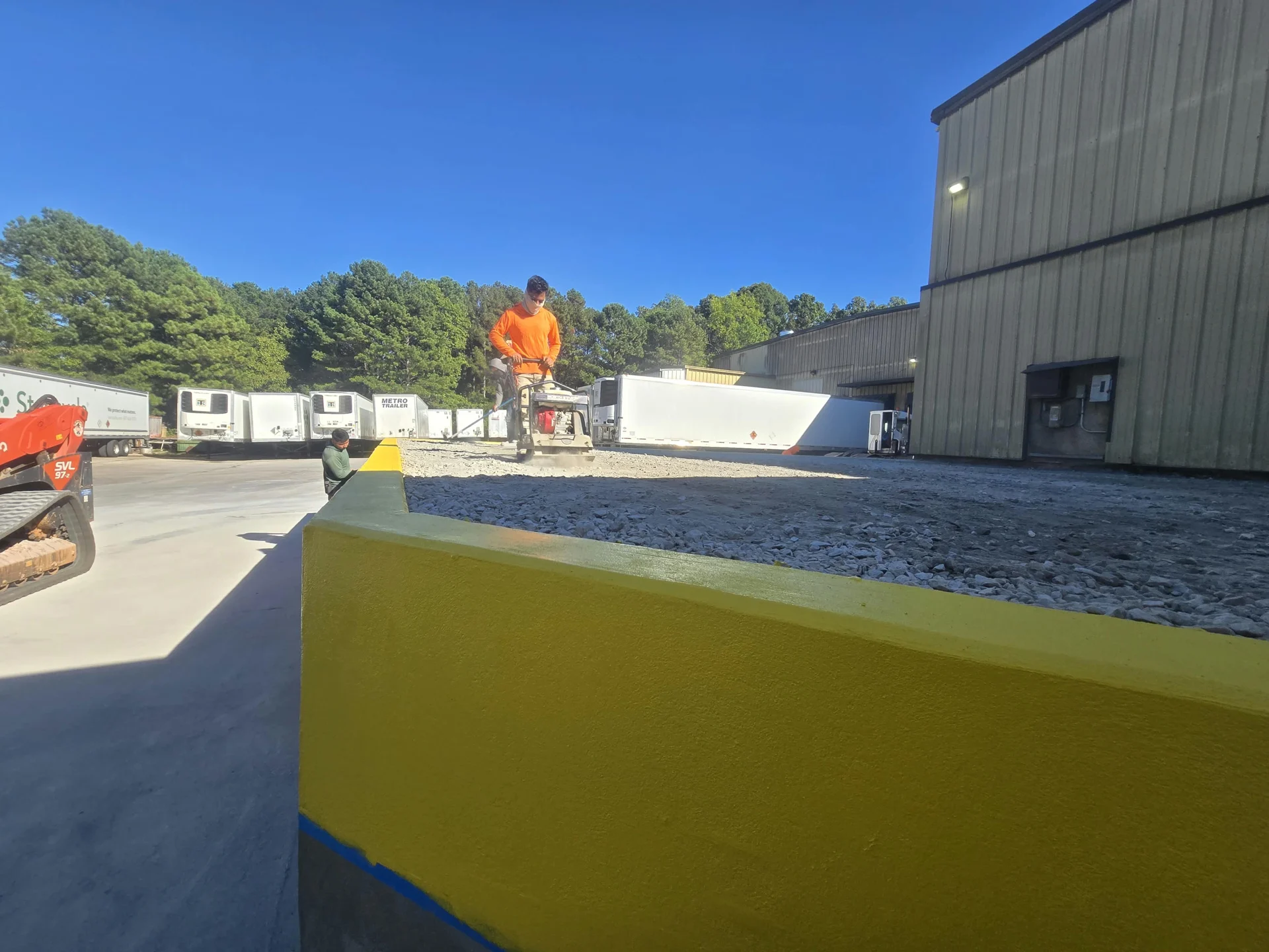 Worker compacting aggregate behind the yellow-painted wall